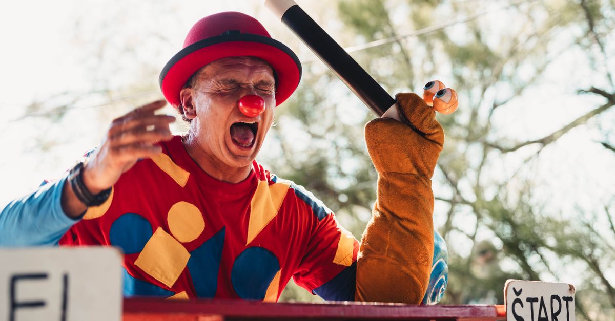 Vibrant clown in colorful outfit entertaining at an outdoor fair.